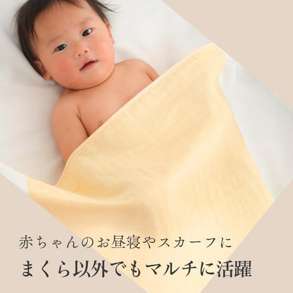 黄色いまくらカバーにくるまれた赤ちゃん。「赤ちゃんのお昼寝やスカーフに」「まくら以外でもマルチに活躍」の文字が入っている